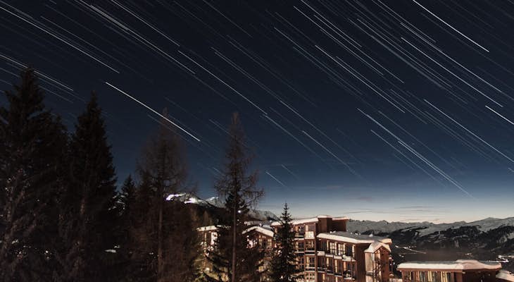  Exposure photograph of star trails with mountain background and chalets in Les Arcs 