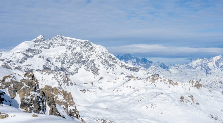 View of a snow covered mountain range with light cloud cover