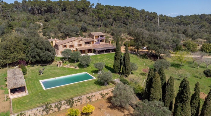 Finca Mas Gotas Aerial view of a large house surrounded by trees, with a rectangular pool and landscaped garden in the foreground.