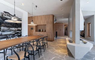 Saint-Tropez - 3 Mallorca accommodation - Villa Printania - Modern dining area with a long wooden table, black chairs, pendant lights, and a stone floor. The space features wooden paneling, a built-in shelving unit, and minimalist decor elements.