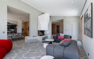Saint-Tropez - 2 Mallorca accommodation - Villa Printania - Modern living room with gray sectional sofa, geometric stone flooring, red accent chairs, abstract wall art, and a view into the adjacent dining area.