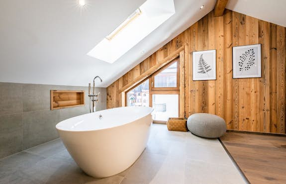Elegant mansard-roofed bathroom with master oval bathtub in Apartment Ruby, Chamonix