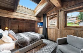 Megeve accommodation - Chalet Orcia - A bedroom with wooden walls and sheepskin rugs.