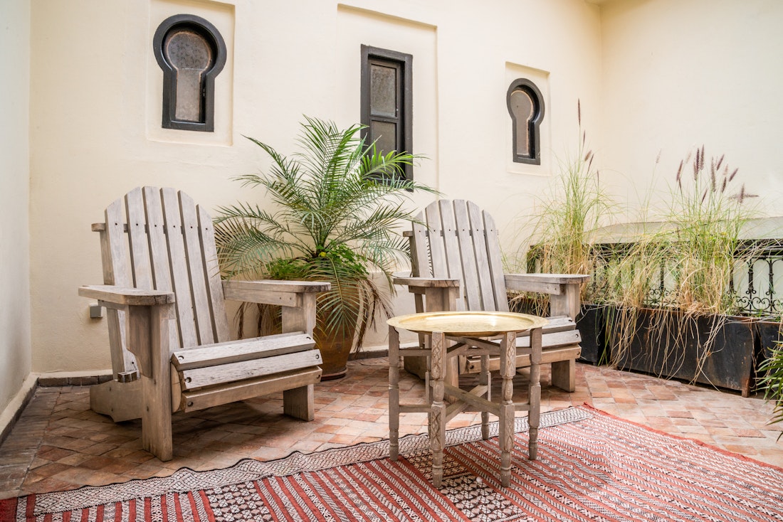 Indoor patio with wooden chairs and berber rug at Adilah riad in Marrakech