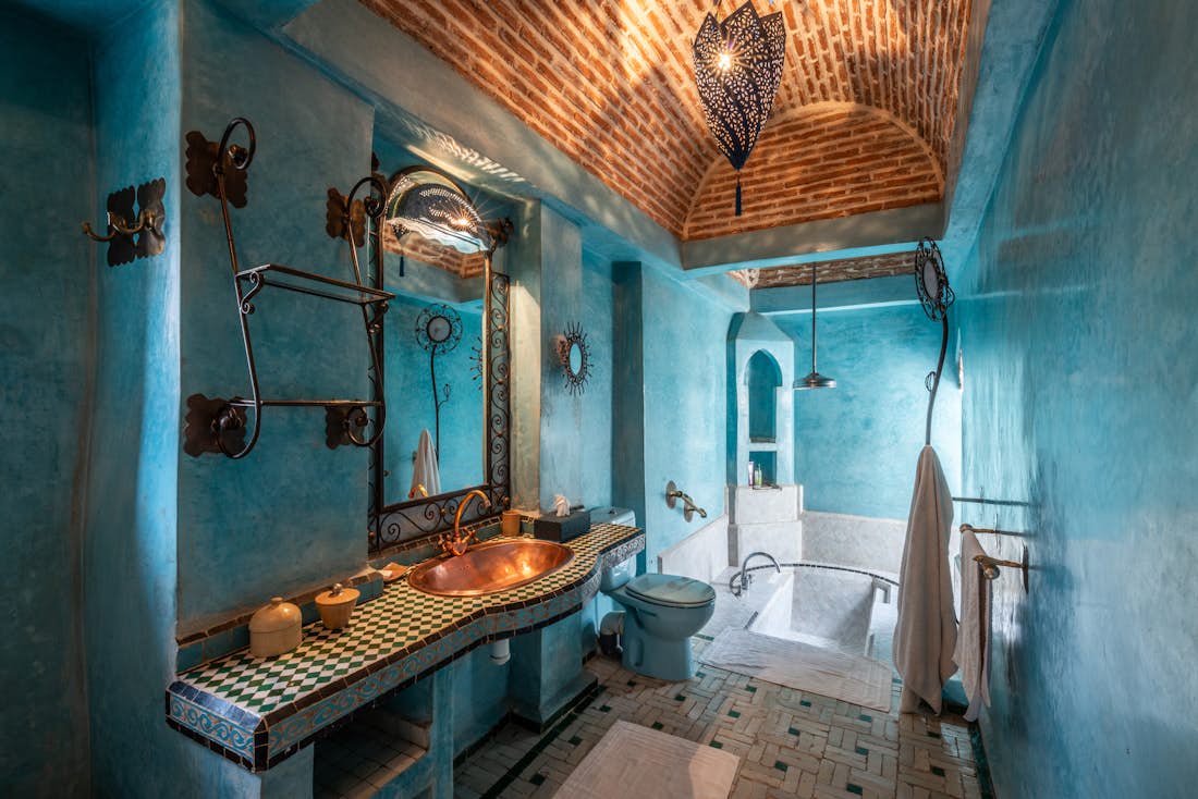 Turquoise blue bathroom with copper sink and moroccan tiles bathtub at Adilah riad in Marrakech