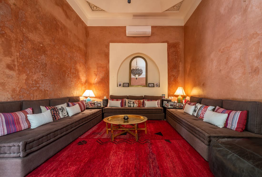 Lounge are with three large brown couches and a red berber rug at Adilah riad in Marrakech