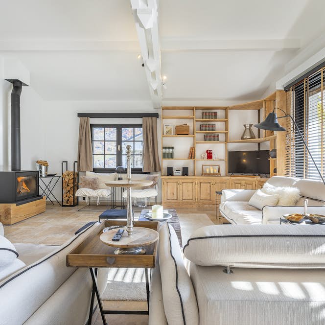 Saint-Gervais-les-Bains - 1 Saint-Gervais accommodation - Chalet Soleil Blanc - Bright living room with a wood-burning stove, beige sofas, a wall-mounted TV, bookshelves, and large windows with blinds.