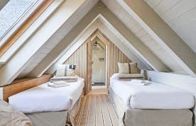 Val de Ruda - 6 Baqueira Beret accommodation - Apartment Nevada - Three-story wooden lodge with multiple dormer windows and balconies, surrounded by trees and a grassy lawn, against a bThree-story wooden lodge with multiple dormer windows and balconies, surrounded by trees and a grassy lawn, against a backdrop of mountains and clear blue sky.ackdrop of mountains and clear blue sky.