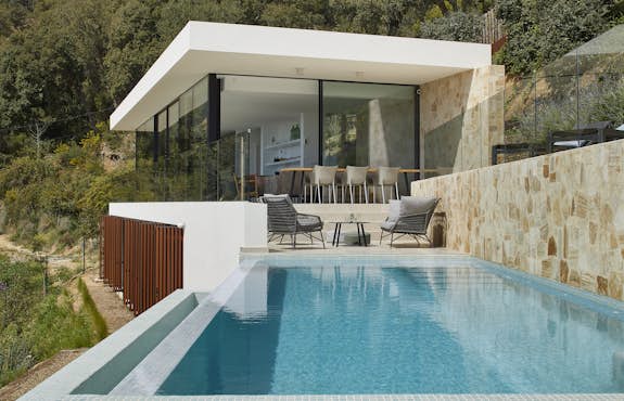 A modern house with a swimming pool on a hillside.