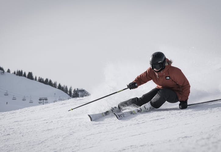Une dame en tenue d'hiver skiant rapidement dans la neige aux Arcs