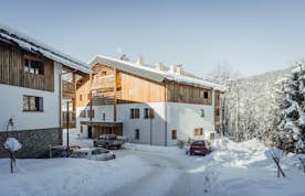 Megeve accommodation - Apartment Opale - Snow-covered road leading to modern chalets in a sunny, mountainous landscape during winter.