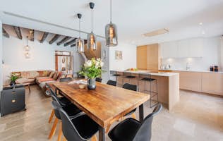 Pollensa - 4 Mallorca alojamiento - RV12 - Modern open-plan kitchen and dining area with a wooden table, black chairs, pendant lights, and large windows overlooking a patio and small pool