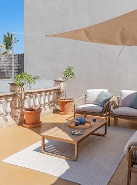 Pollensa - 5 Mallorca accommodation - Ca Na Rieres - Sunny outdoor terrace with green lounge chairs, potted plants, seating area, and sunshade, surrounded by white walls and a tiled floor.