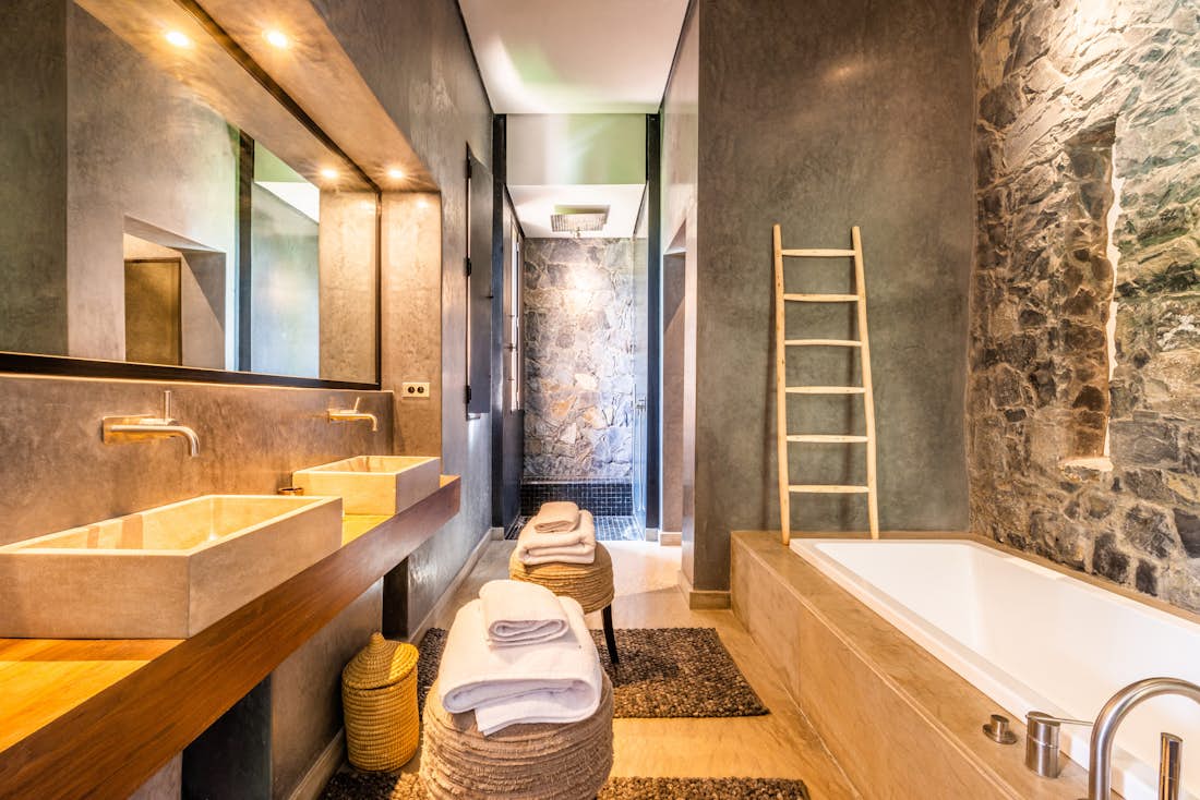 Ethnic and industrial style bathroom with concrete sinks and wooden bathroom furnitures at Marhba luxury private villa in Marrakech