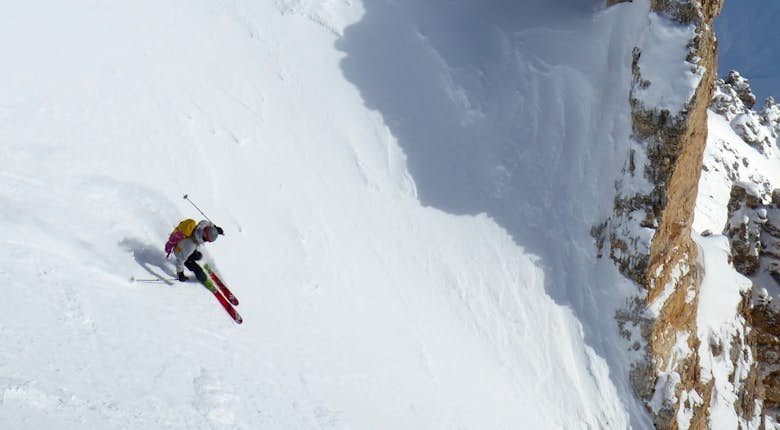 A skier going down a snow covered slope.