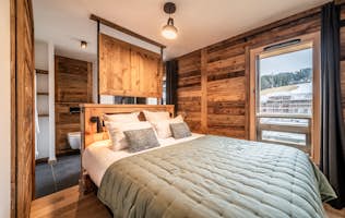 Les Gets accommodation - Apartment Pamir - A bedroom with wooden walls and a wooden bed.