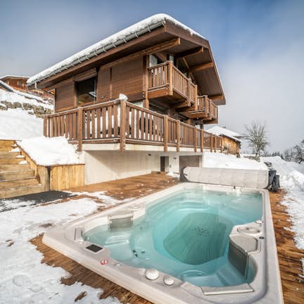 A hot tub in the snow next to a house.