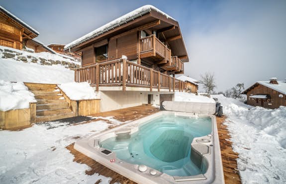 A hot tub in the snow next to a house.