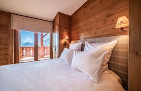 Verbier alojamiento - Apartmento Ayous - A wooden bedroom with a bed and a balcony.