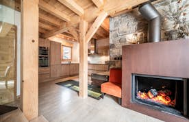 Chamonix location - Chalet Inari - A living room with a wooden staircase and a dining table and a fireplace.