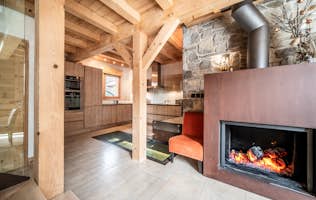 Chamonix accommodation - Chalet Inari - A living room with a wooden staircase and a dining table and a fireplace.
