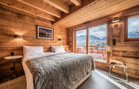 Morzine accommodation - Chalet Heavenly - A bedroom in a log cabin with a view of the mountains.