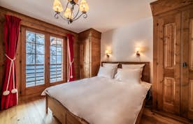 Verbier accommodation - Apartment Ayous - A wooden bedroom with a bed and a balcony.
