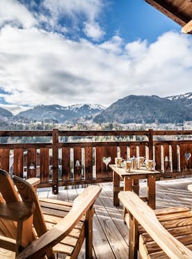 Morzine accommodation - Chalet Heavenly - A wooden deck with chairs and a view of the mountains.