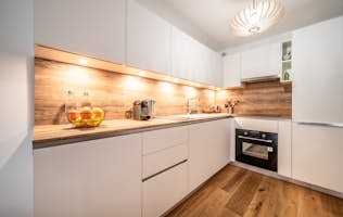 Alpe d’Huez alojamiento - Apartamento Edelweiss - A kitchen with white cabinets and wood floors.