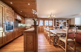Verbier location - Appartement Ayous - A kitchen with wooden floors and a dining table.