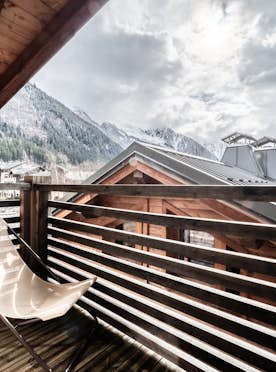 Chamonix accommodation - Chalet Inari - A wooden chair on a balcony overlooking the mountains.