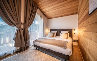 Morzine accommodation - Chalet Bellatrix - A wooden bedroom with a bed and a yellow blanket.