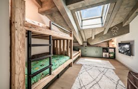 Châtel - 6 Châtel location - Appartement Nightfall - A cozy attic bedroom with wooden bunk beds, a skylight, green built-in cabinets, a rug, and children's decor on the walls.
