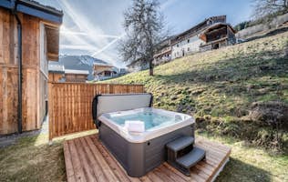 Morzine accommodation - Chalet Bellatrix - A wooden house with a hot tub in front of it.