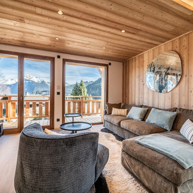 Morzine accommodation - Chalet Bellatrix - A living room with a fireplace and a view of the mountains.