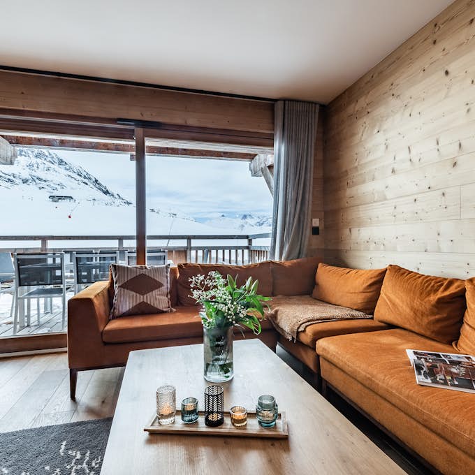 A bedroom with wooden walls and a balcony overlooking the mountains.