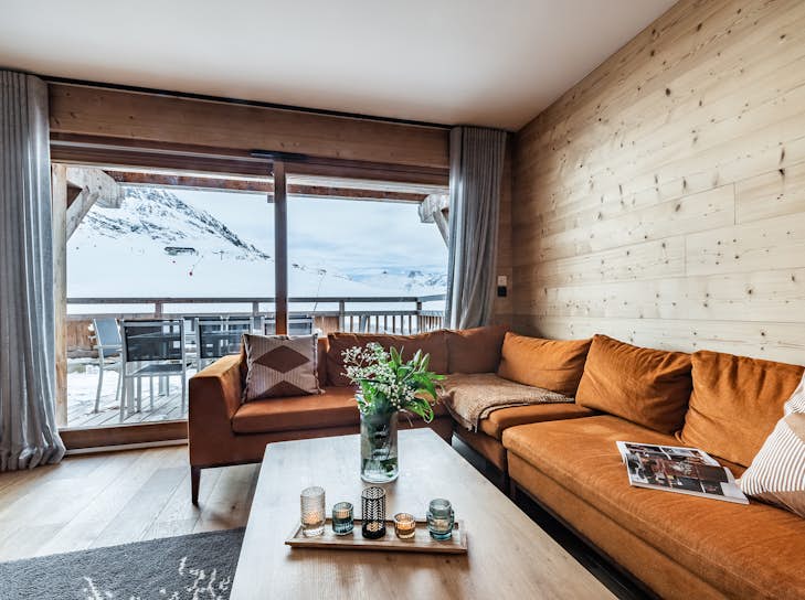 Grand Massif Property management A bedroom with wooden walls and a balcony overlooking the mountains.