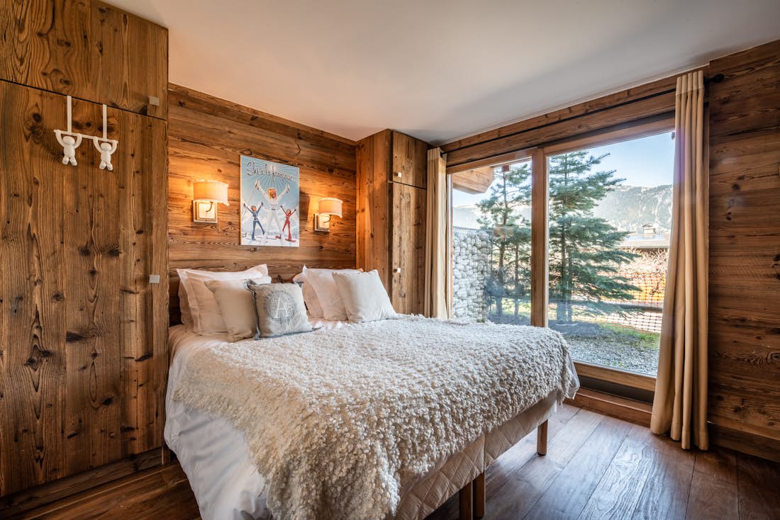 Courchevel accommodation - Apartment Moabi - Wood panelled double bedroom with chest of drawers and landscape views at ski in ski out apartment Moabi Courchevel Le Praz