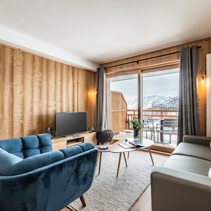 Alpe d’Huez Grand Domaine  Property management A living room with a view of the mountains.
