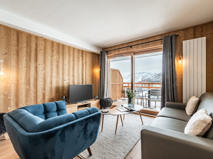 Conciergerie Alpe d'Huez A living room with a view of the mountains.