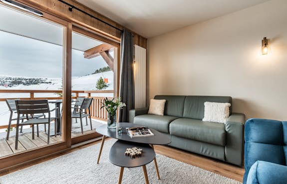 A living room with a balcony overlooking a snowy mountain.