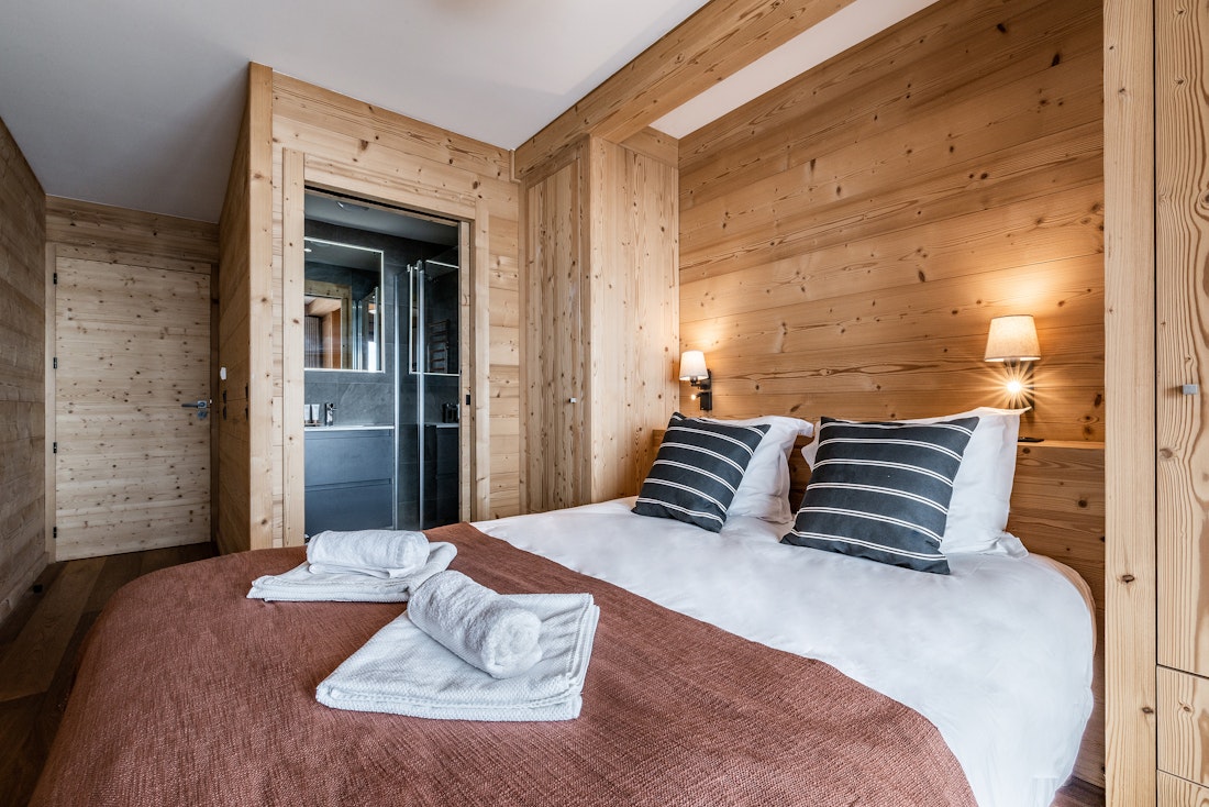 Chambre en suite avec murs en bois et serviettes propres dans la location Wapa à l'Alpe d'Huez