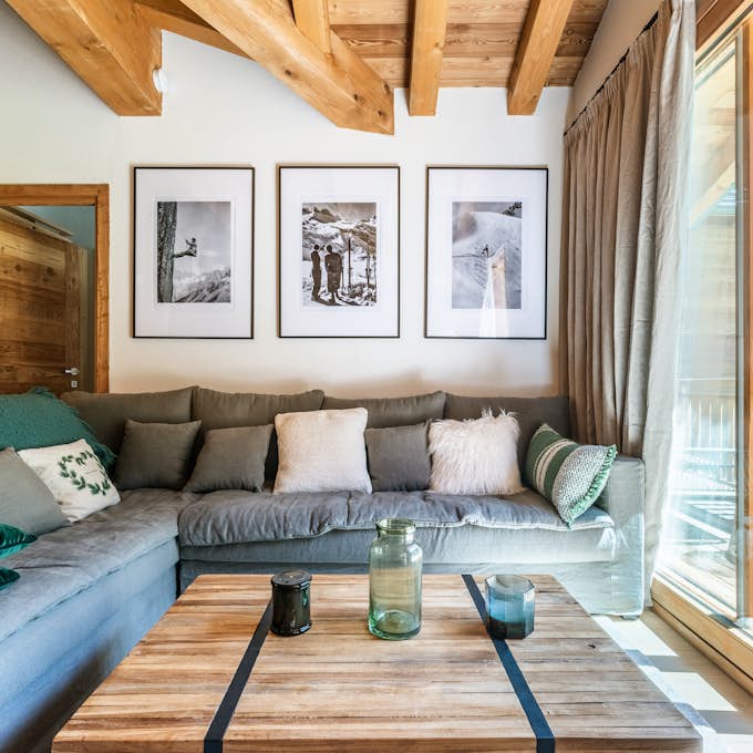 Conciergerie Chamonix A living room with wooden beams and a view of the mountains.