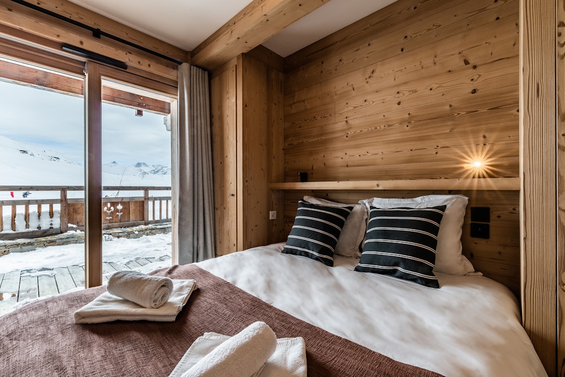 Chambre double en bois avec serviettes dans la location Wapa à l'Alpe d'Huez