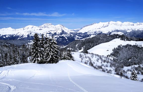A view of a snow covered slope with mountains in the background