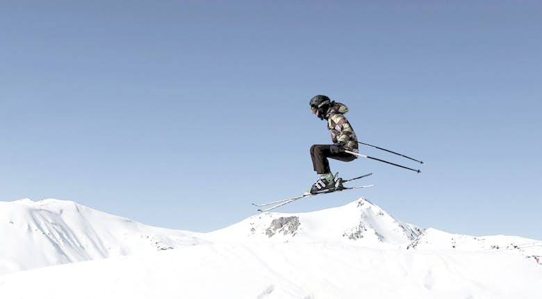 A skier in the air over a snow covered mountain
