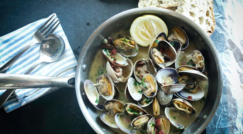 Clams in a pan with bread and lemon