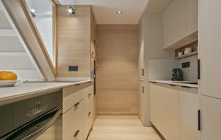 Val de Ruda - 3 Baqueira Beret accommodation - Apartment Nevada - Modern open-concept kitchen and living area with wooden floors and ceiling beams. The kitchen features sleek cabinetry and a large island, while the living room has large windows and cozy seating.