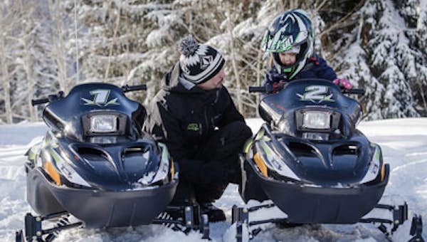 A father guiding his son on the electric snowmobile activity in Les Arcs