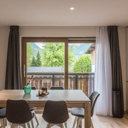 A dining room with a wooden table and chairs and a view of the mountains.
